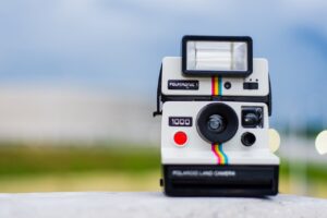 una foto de una cámara polaroid apoyada en una piedra