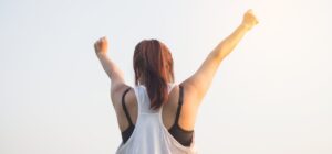 chica de espaldas celebrando con los brazos levantados