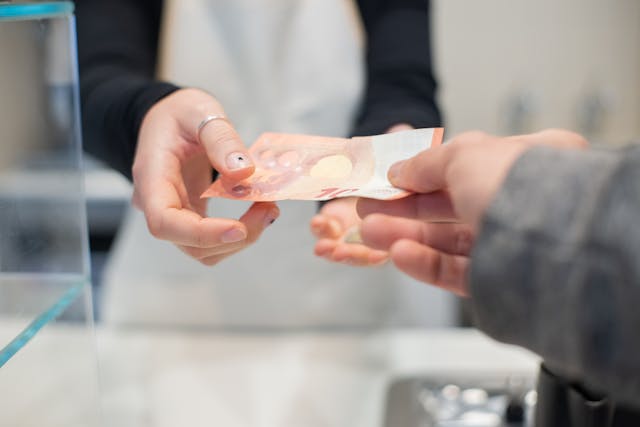 una persona entregándole un billete de 10 euros a otra persona
