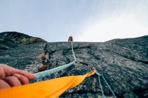 el punto de vista de una persona escalando una montaña usando un arnés. Su compañero/a está más arriba